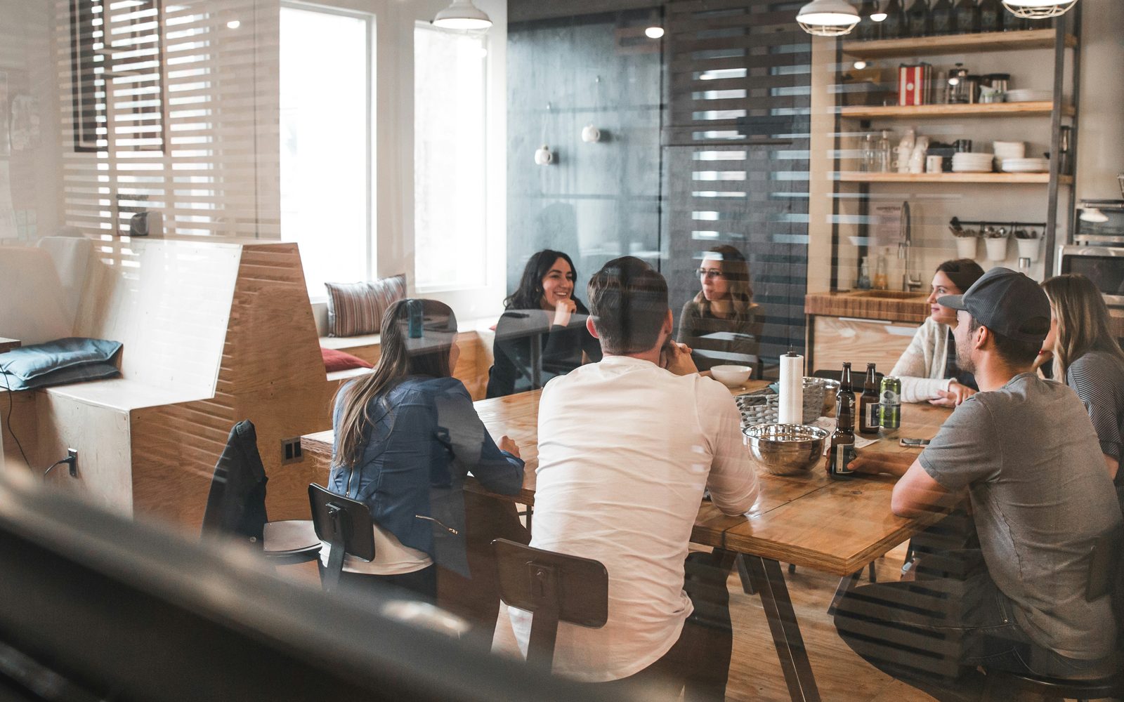 A team talking around a wooden table in a bright workspace